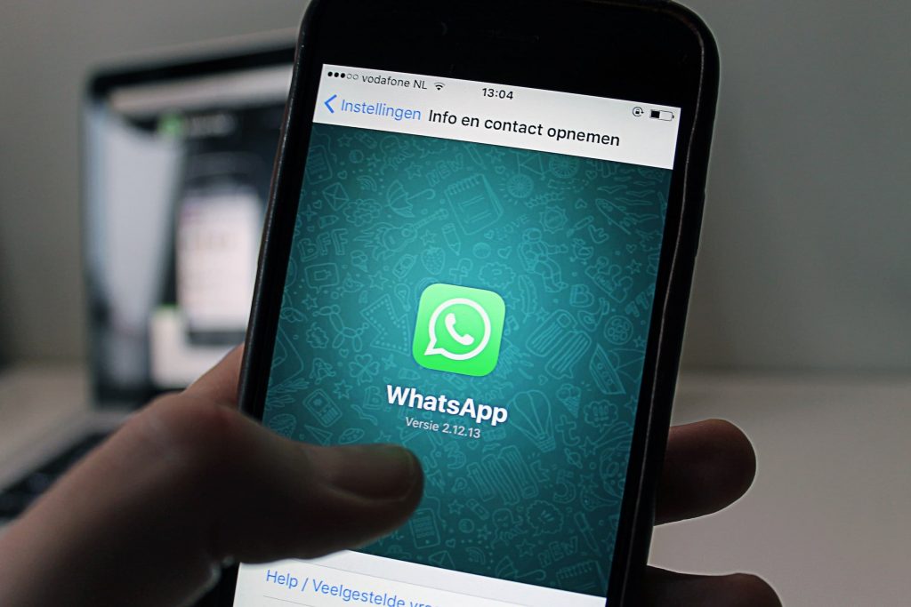 Hand met een smartphone waarop WhatsApp is geopend