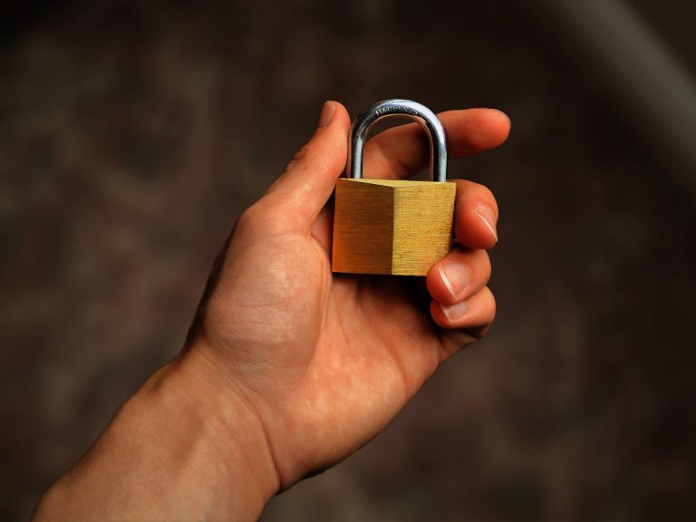 Hand houdt een koperen hangslot vast