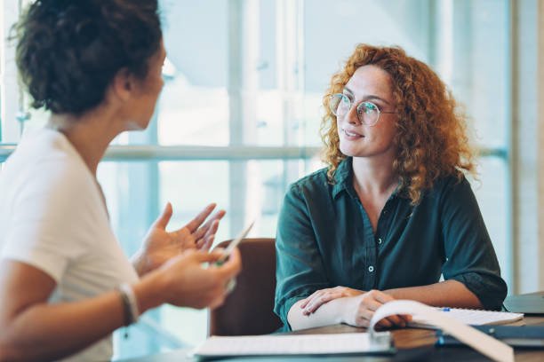 Adviseur luistert naar haar klant tijdens een gesprek aan tafel bij het raam