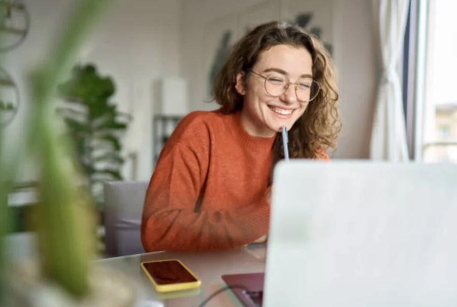 Ondernemer die lachend achter haar laptop werkt