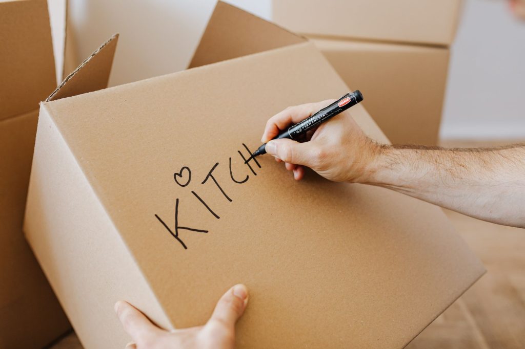 Hand schrijft met een marker op een verhuisdoos