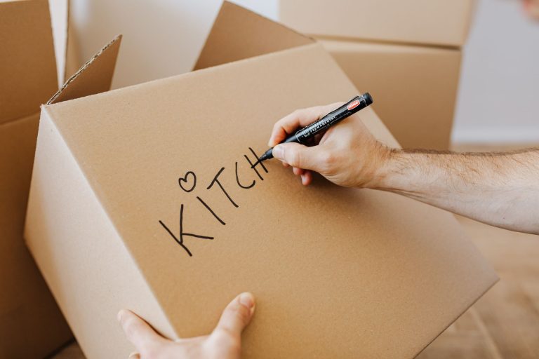 Hand schrijft met een marker op een verhuisdoos
